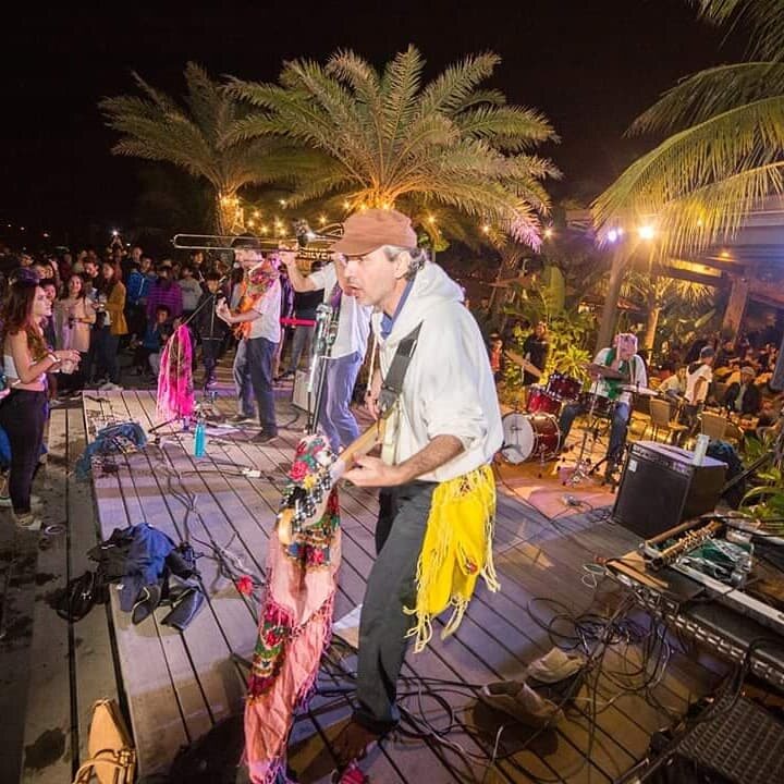 Balkazar performing beside a dancing crowd under palm trees