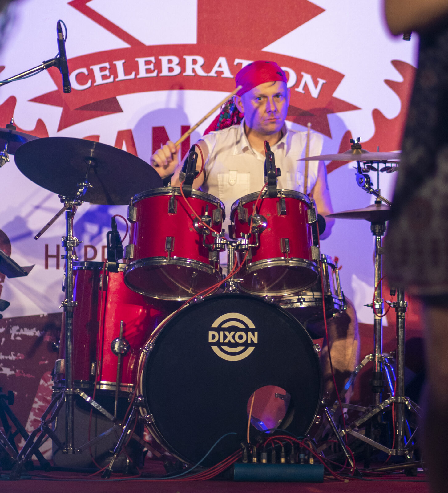 Drummer performing live with a maple leaf stage backdrop