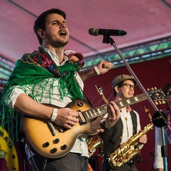 Balkazar's singer and saxophonist performing under warm stage lights